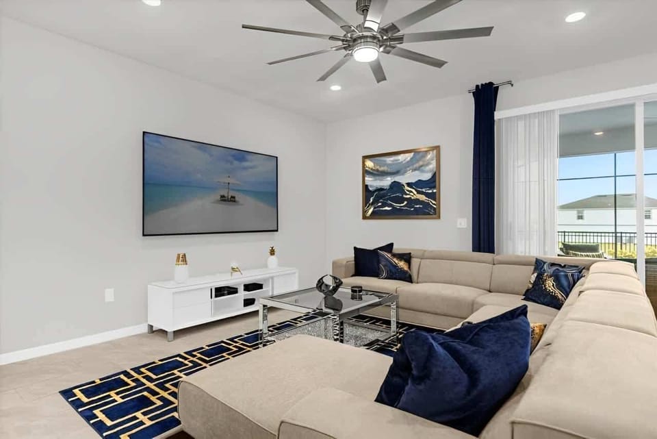 Spacious modern living room with plush sectional, smart TV, and poolside views.