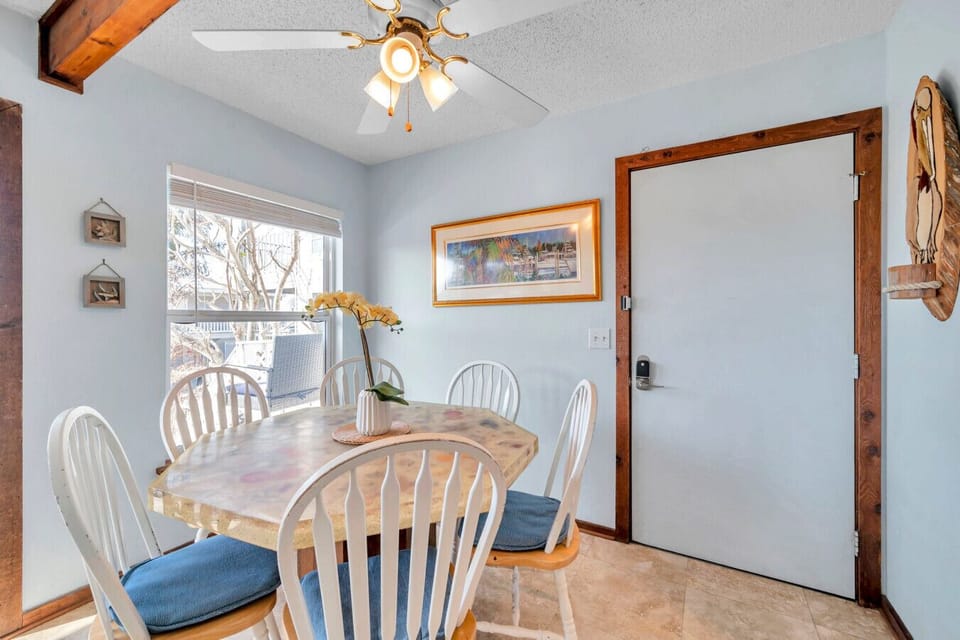 Sunlit dining area w/ a round table and coastal touches, ideal for relaxed meals together.