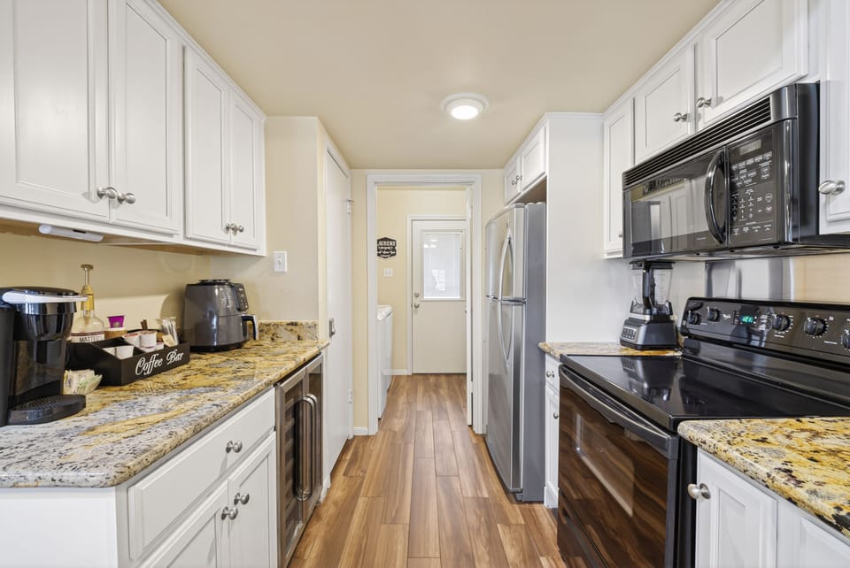 Modern kitchen with stainless appliances, coffee bar & granite counters.