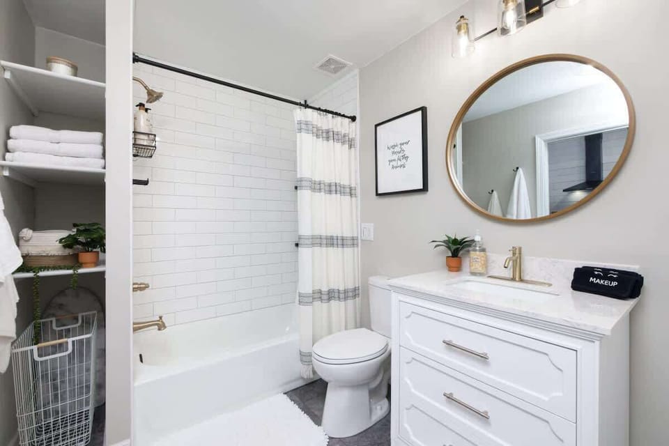 Bathroom w/ vanity, round mirror & shower curtain for a clean, fresh feel