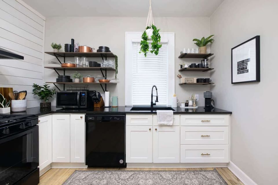 Modern kitchen w/ black appliances, white cabinets & open shelving for easy access