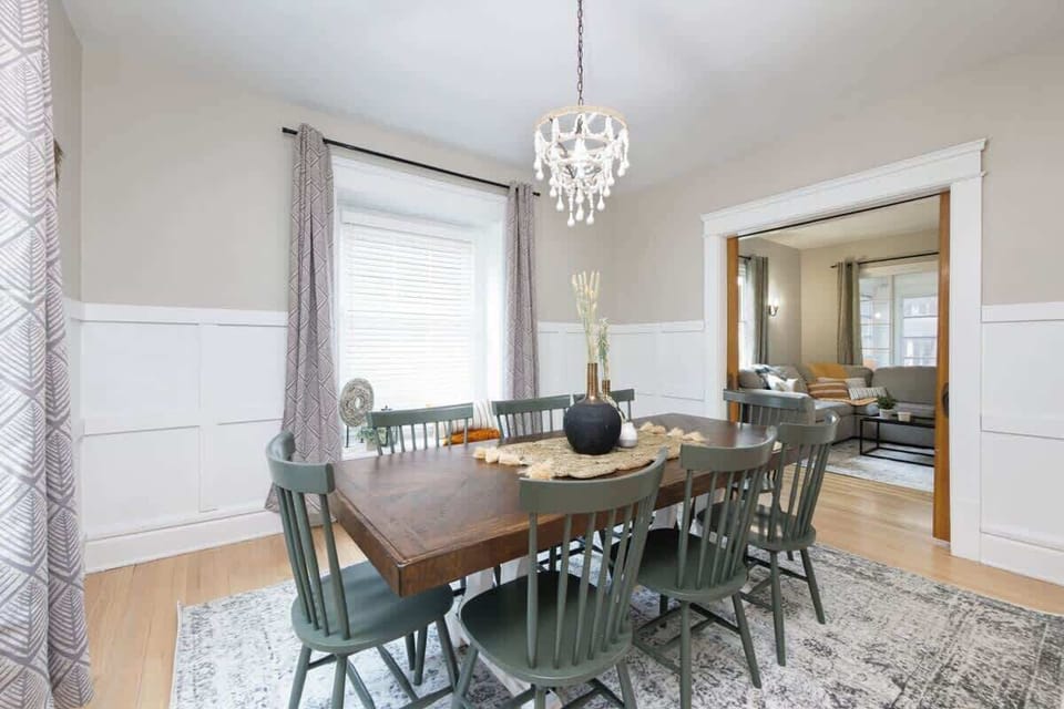 Dining area w/ table for group meals, set beside windows for a light-filled gathering space