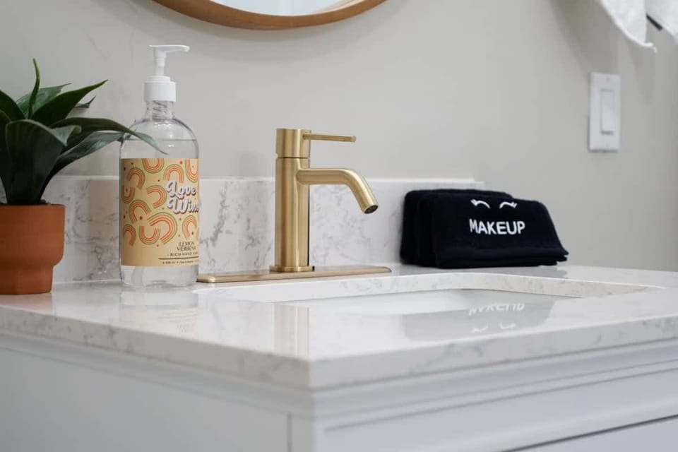Bathroom counter w/ sink, gold fixtures & neatly styled essentials