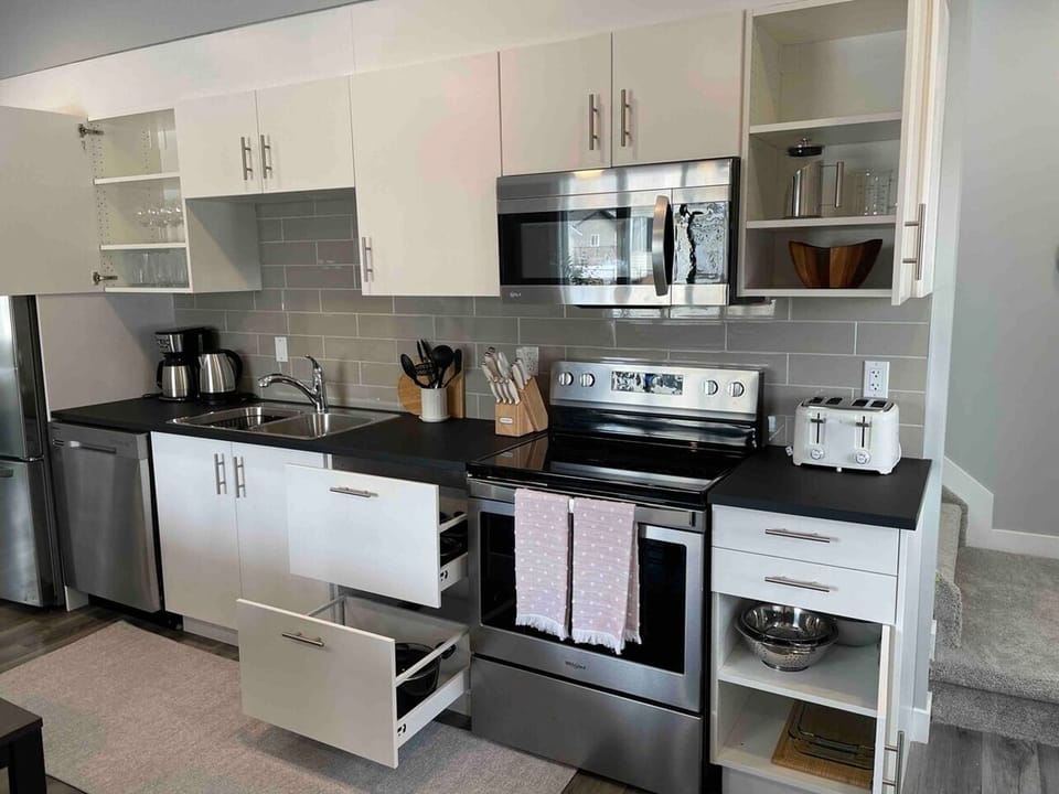 Modern and Inviting: A Kitchen Oasis with White Cabinets, Black Countertops, and Sleek Appliances