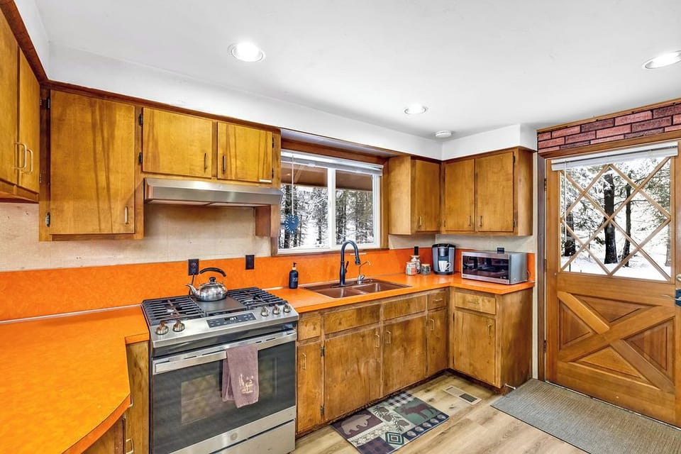 A vintage kitchen with wooden cabinets and a snowy window view.