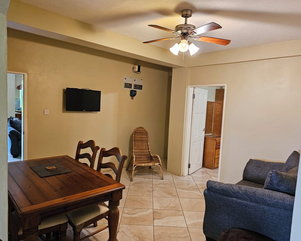 Bright living & dining area with cozy sofa, smart TV, and table for relaxing.