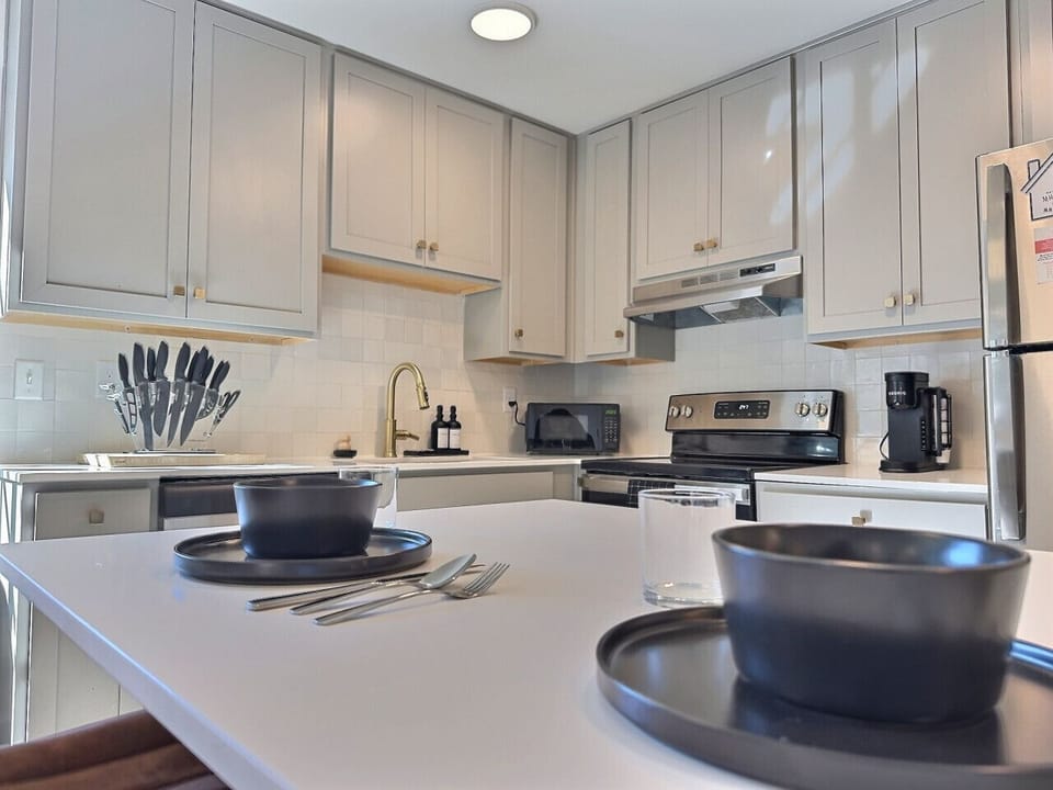 Modern kitchen with sleek stainless steel appliances and neatly arranged utensils, perfect for effortless cooking during your short-term rental stay.