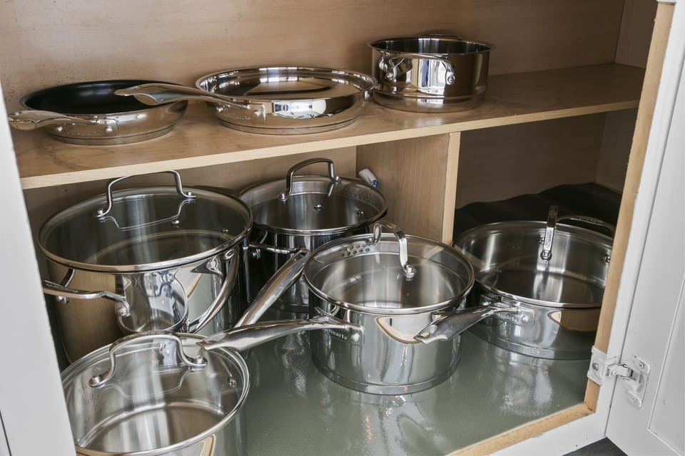 Base cabinet gleams with a collection of stainless steel pots and pans.