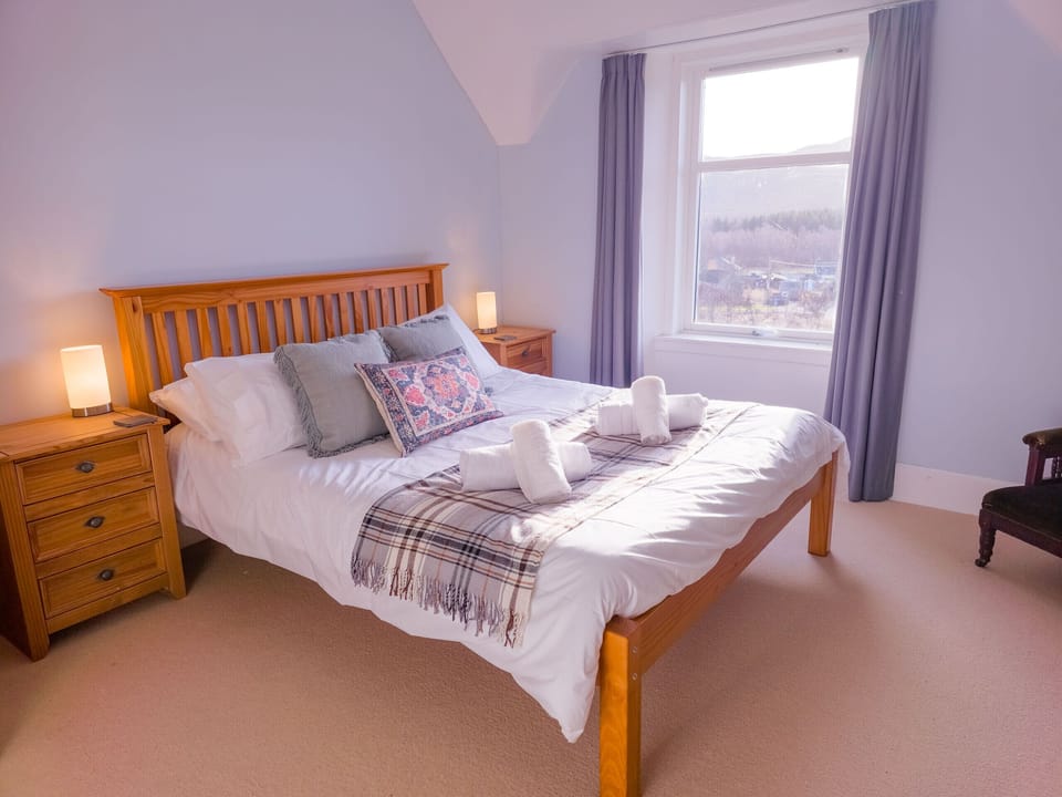 Relax in the master bedroom featuring a comfortable bed and views of the stunning Highland surroundings