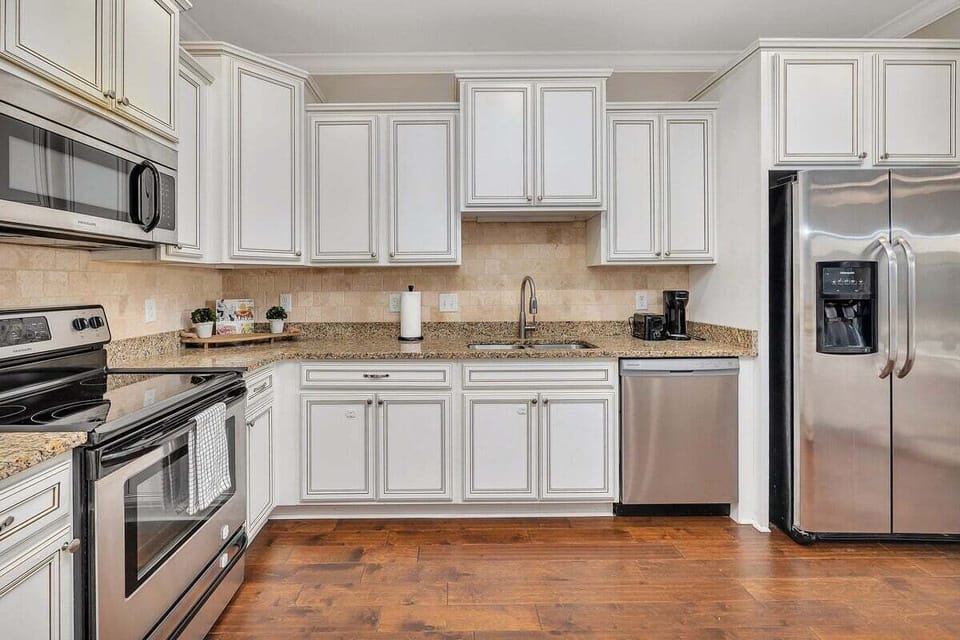 Kitchen with white cabinets, granite counters, and stainless appliances