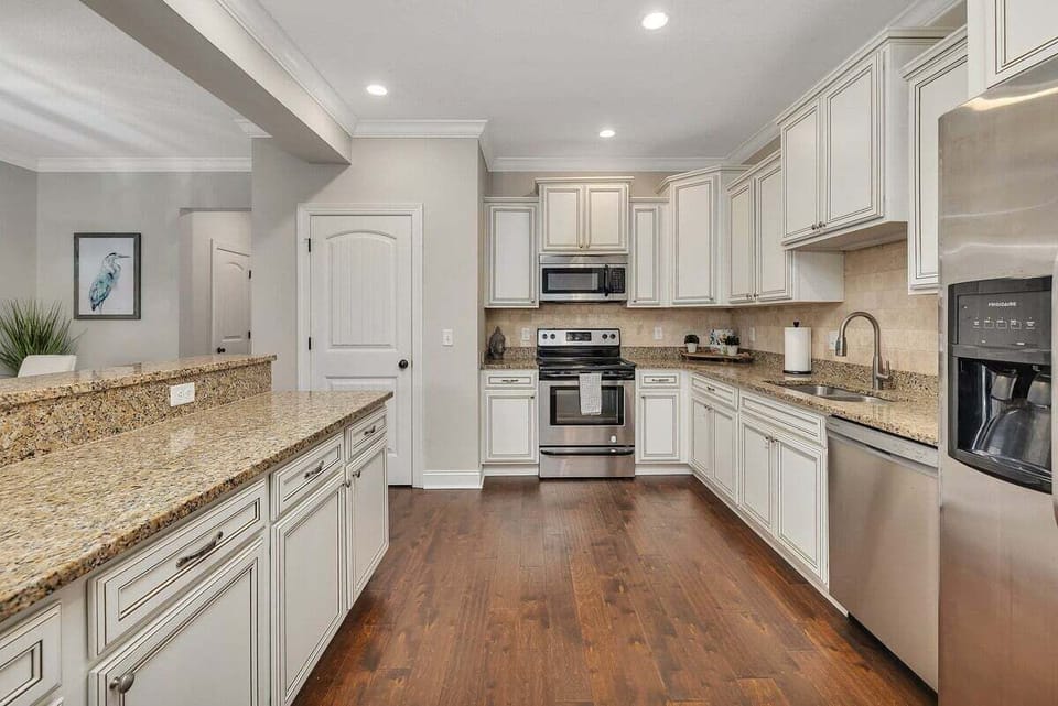 Kitchen with white cabinets, granite island, and hardwood floors