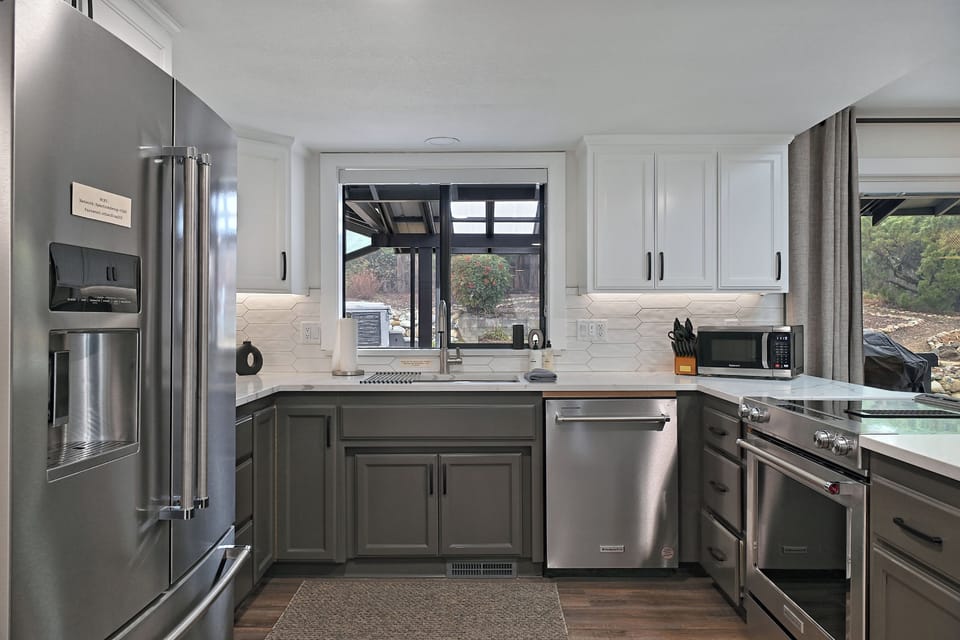 Fully equipped modern kitchen with stainless steel appliances, elegant finishes, and a scenic view of the backyard