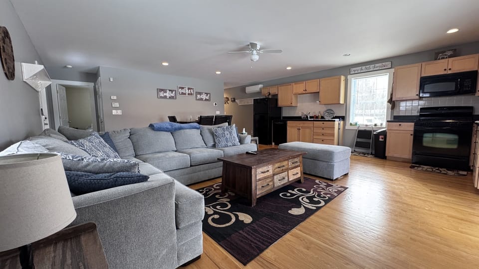 Living room with sizeable L-shaped couch with open concept to kitchen and dining area