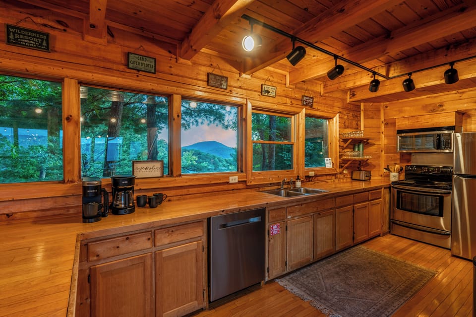 The fully stocked kitchen features a full wall of windows and offers a fridge, freezer, ice maker, oven, stove, microwave, divided sink, and dishwasher