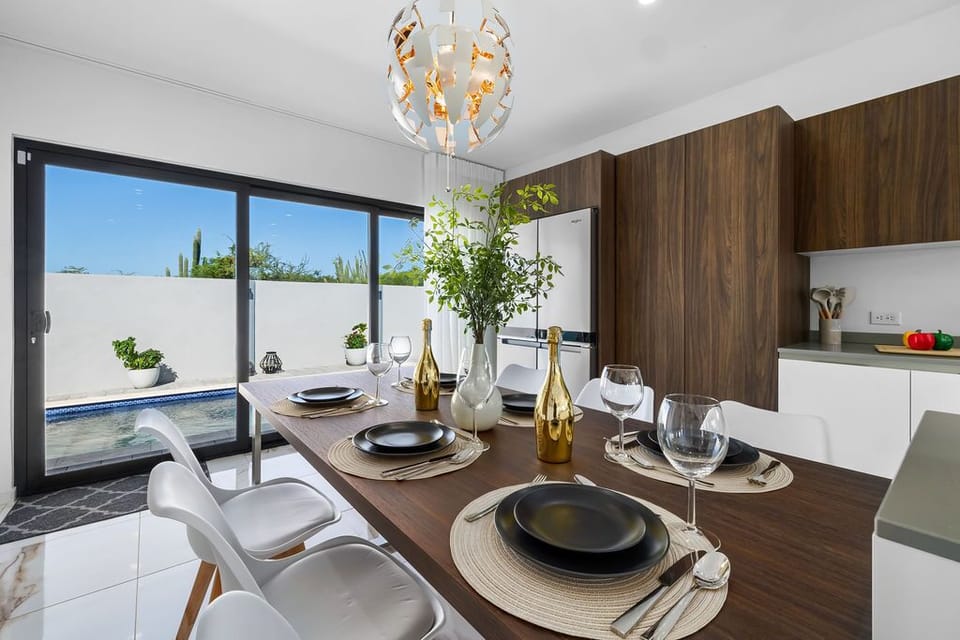 This beautifully designed dining area features modern fixtures, spacious seating, and seamless access to a private outdoor space with a pool—perfect for unforgettable gatherings and tranquil mornings.