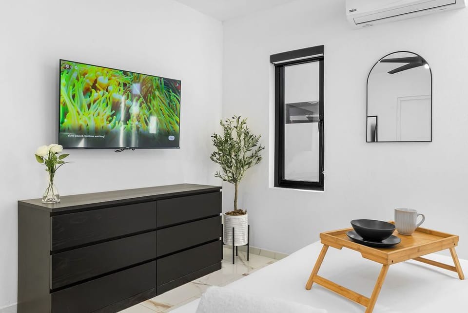 Unwind with the large, wall-mounted flat-screen TV—perfect for movie nights in bed—while the sleek, spacious black dresser offers ample room to unpack and truly feel at home.