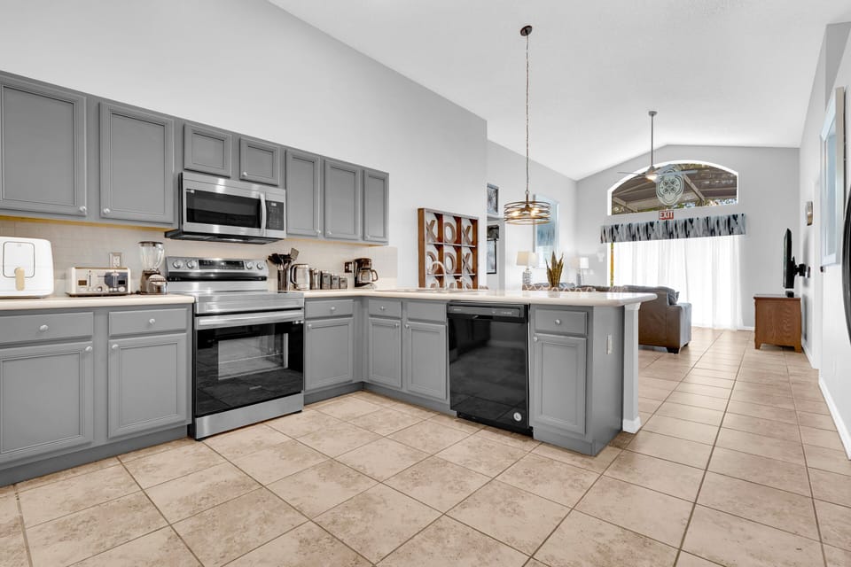 Stylish kitchen at Seasons near Disney features gray cabinetry, full cookware, and a cozy breakfast bar.