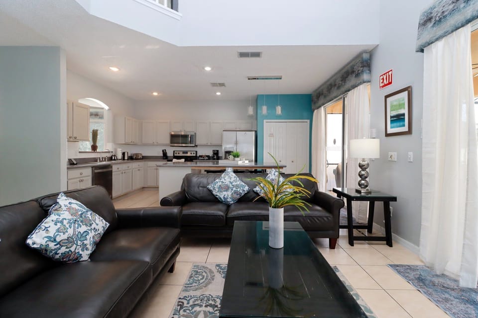 The main living area at the rear of the villa offers two comfortable sofas, a large flatscreen TV, and direct access to the pool deck through sliding glass doors.