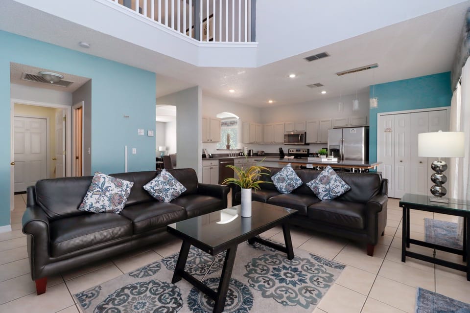 The main living area at the rear of the villa offers two comfortable sofas, a large flatscreen TV, and direct access to the pool deck through sliding glass doors. A bright, welcoming space.