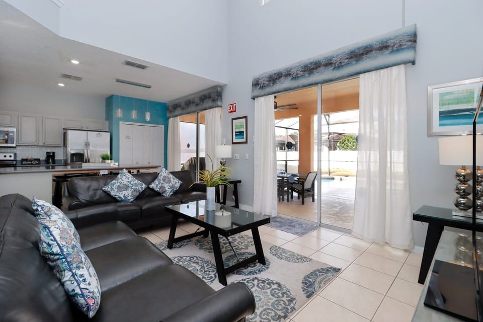 The main living area at the rear of the villa offers two comfortable sofas, a large flatscreen TV, and direct access to the pool deck through sliding glass doors.