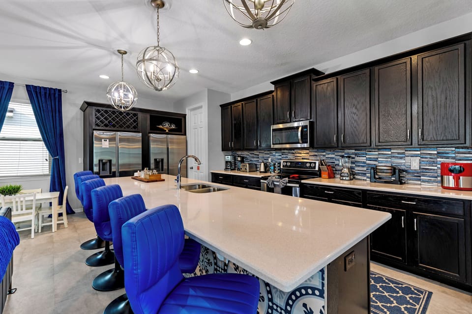This stylish kitchen features dark cabinetry, a spacious island, and seating for six—perfect for casual breakfasts, evening cocktails, or serving up a buffet for the whole crew.