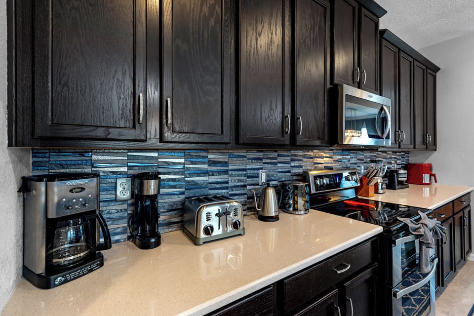 This stylish kitchen features dark cabinetry, a spacious island, and seating for six—perfect for casual breakfasts, evening cocktails, or serving up a buffet for the whole crew.