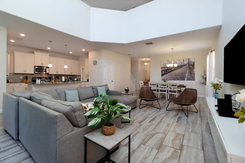A tastefully designed open-concept living area featuring a sectional couch, chairs, flat-screen TV and vaulted ceilings.