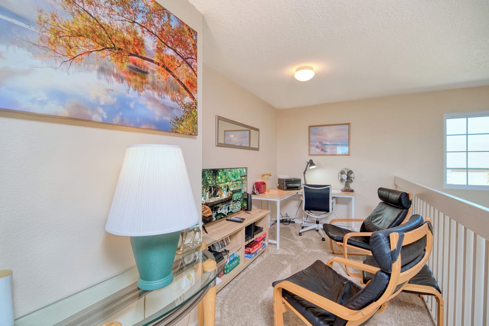 Upstairs landing with TV, comfy seating, and a desk—great for remote work or a quiet movie break.