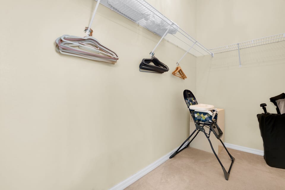 Large closet with hanging space, assorted hangers, and a high chair — ideal for family stays near Disney in Orlando, Florida.
