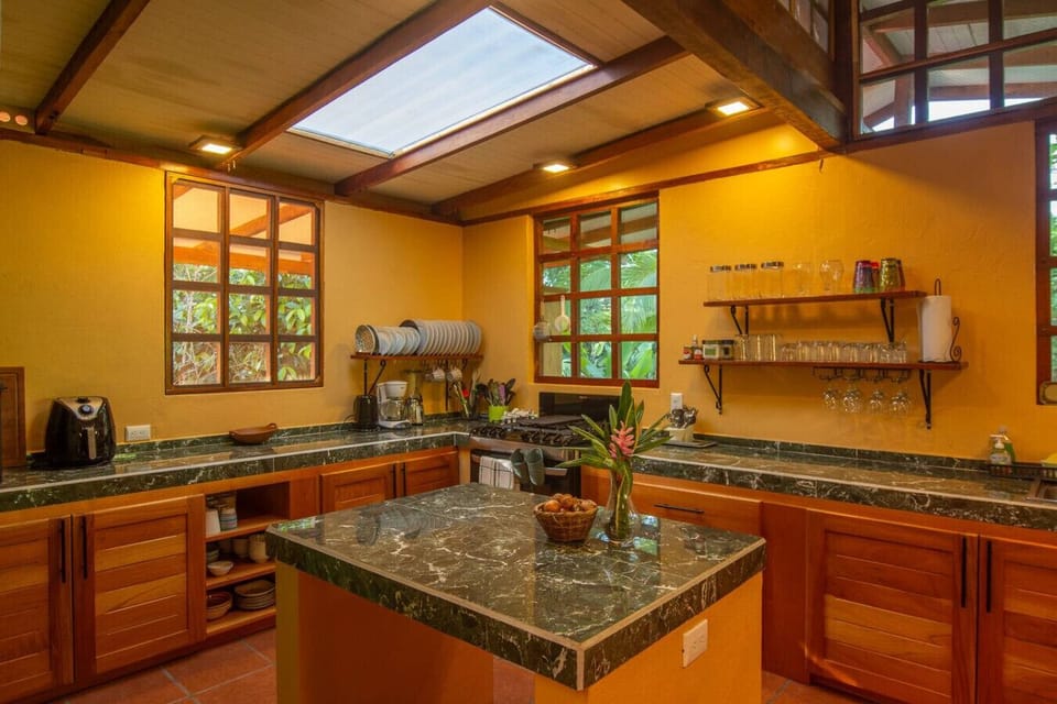 Spacious kitchen with central island, open shelving, and natural light from skylight in Playa Chiquita, Casa Rakú