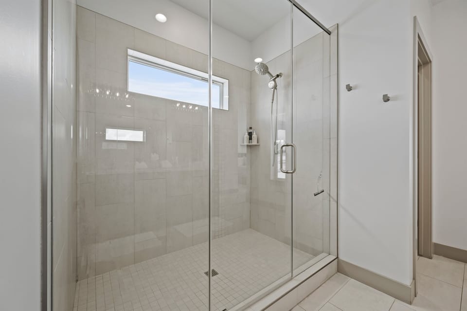 Experience the spacious shower enclosed with a sleek glass door.