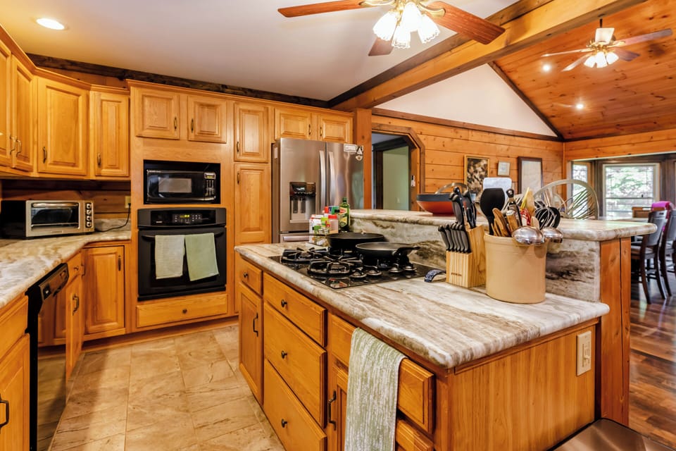 Central kitchen island with a gas stovetop, surrounded by elegant cabinetry and vaulted ceilings.