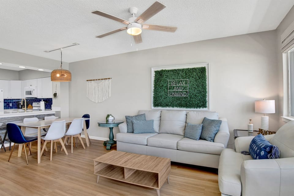 Living room with wall mounted smart tv,  leather sleeper sofa, 2 leather arm chairs, access to the beachside balcony and an AMAZING Gulf view