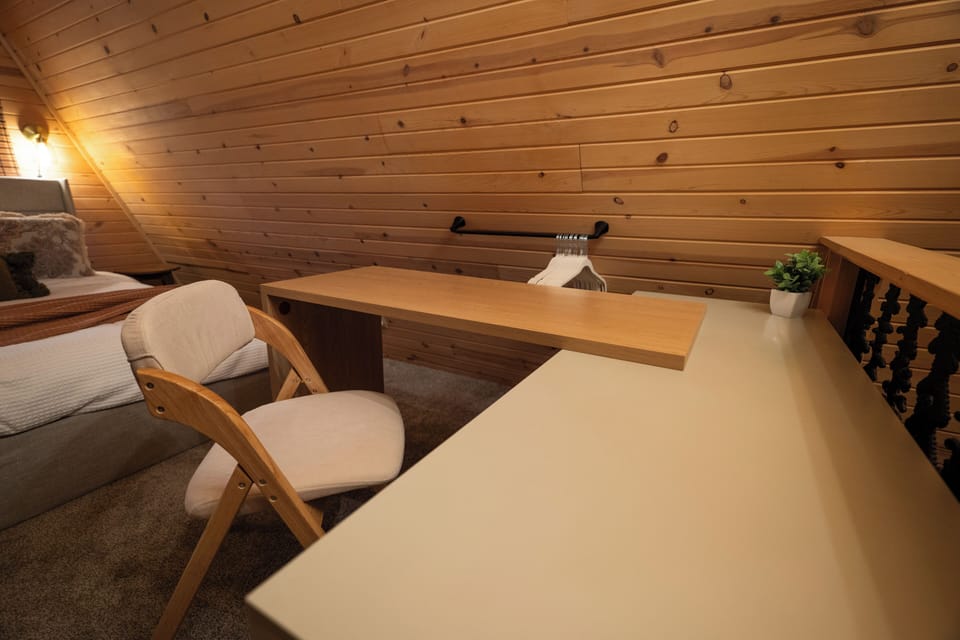 In the primary bedroom, you’ll find a dresser with a swivel top that effortlessly converts to a desk, as well as a cushioned folding chair under the upholstered storage bed, turning this into a multi-function dedicated workspace.