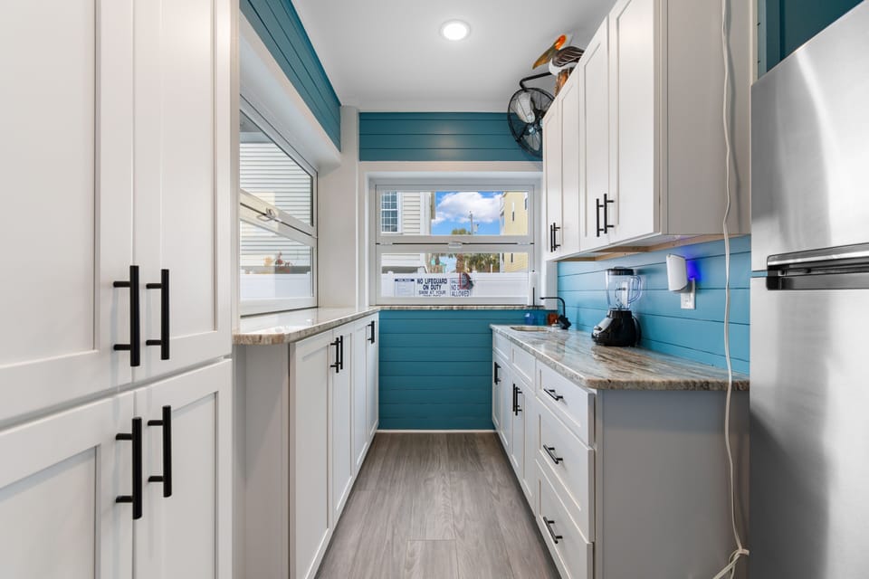 Your fully equipped outdoor kitchen/bar features vibrant teal accents and modern appliances, making meal prep a joy with granite countertops and ample storage space.
