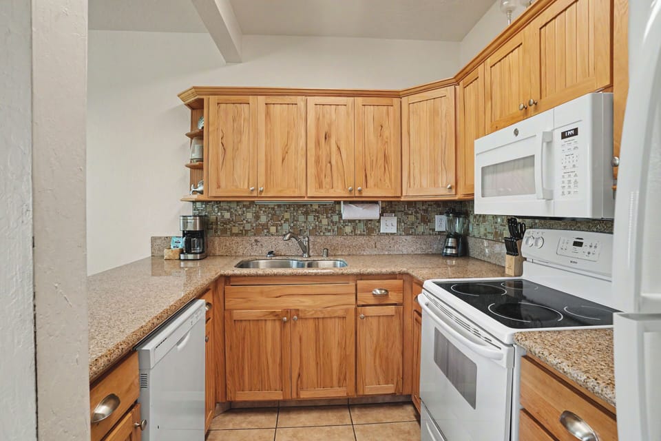 Your well-equipped kitchen features warm wood cabinetry, granite counters, and full appliances including a dishwasher and microwave—everything you need to prepare meals during your stay.