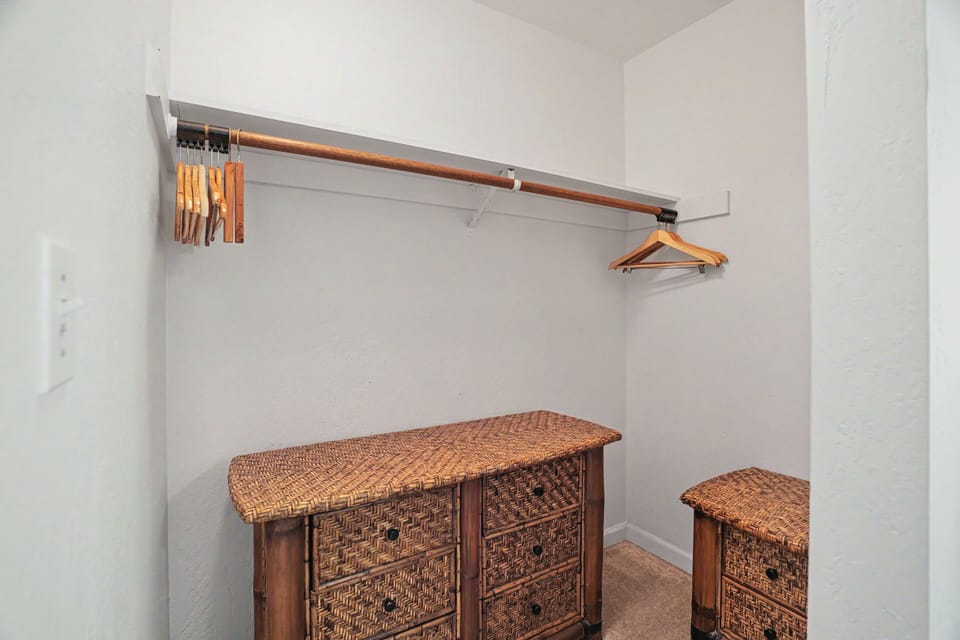 A spacious walk-in closet awaits your wardrobe, featuring ample hanging space and elegant wicker storage chests to keep your belongings organized during your stay.