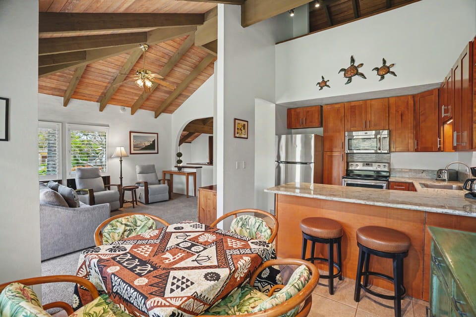 Picture yourself relaxing in this open-concept island retreat, where vaulted wooden ceilings and tropical décor create a breezy, authentic Hawaiian atmosphere. Your fully equipped kitchen flows seamlessly into comfortable living and dining areas.
