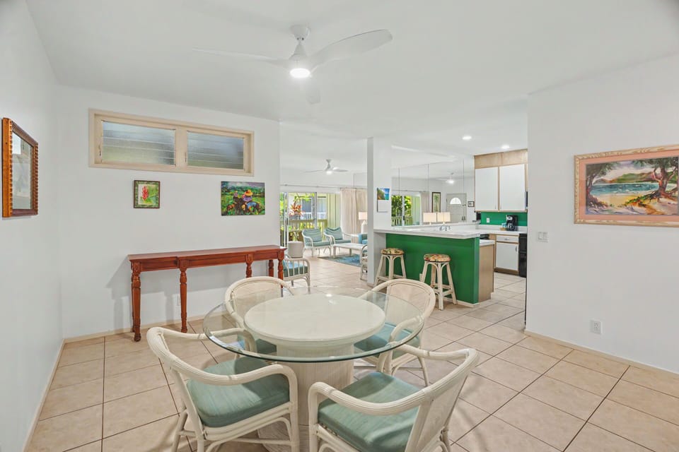 Bright, beachy living with a pop of island color. Your tropical getaway features an open-concept layout with dining, kitchen bar, and living areas—perfect for group meals and relaxed evenings under gentle ceiling fans.
