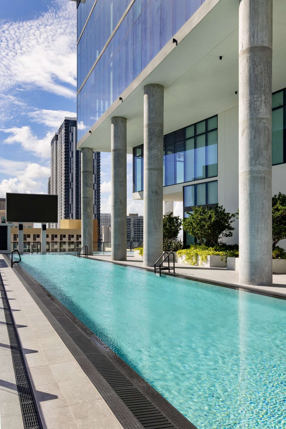 Long outdoor pool beside a high-rise building.