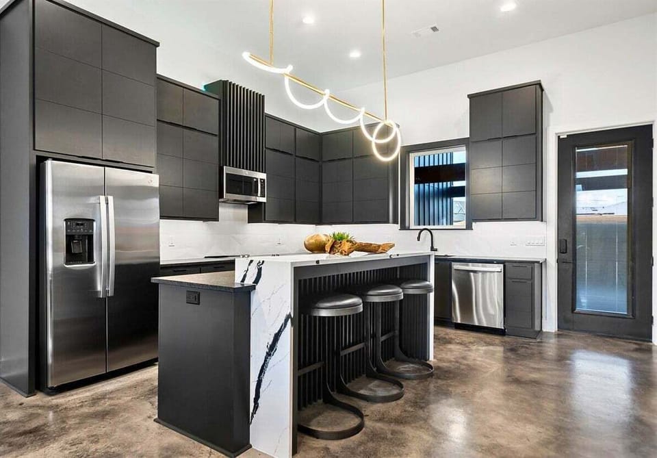 This sleek, modern kitchen is a chef's dream with high-end appliances, a spacious island for casual dining or meal prep, and clean, minimalist finishes that tie the space together.