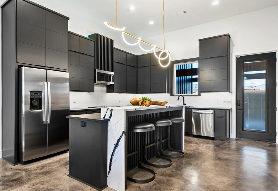 This sleek, modern kitchen is a chef's dream with high-end appliances, a spacious island for casual dining or meal prep, and clean, minimalist finishes that tie the space together.