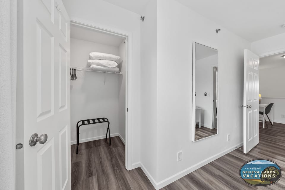 Large closet for clothing with luggage rack, hangers, and extra pillows