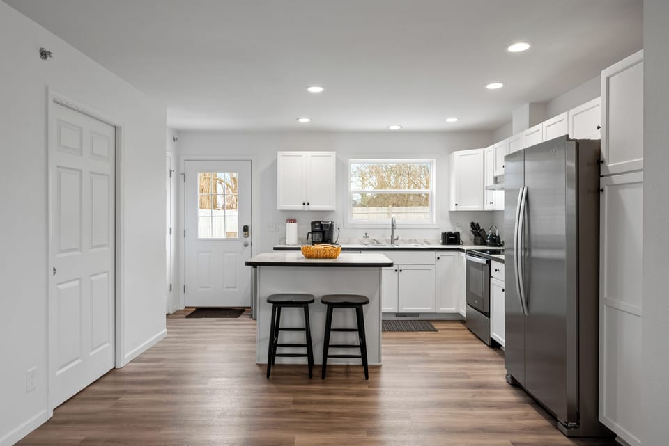 Kitchen fully equipped with island seating, Door to access backyard.