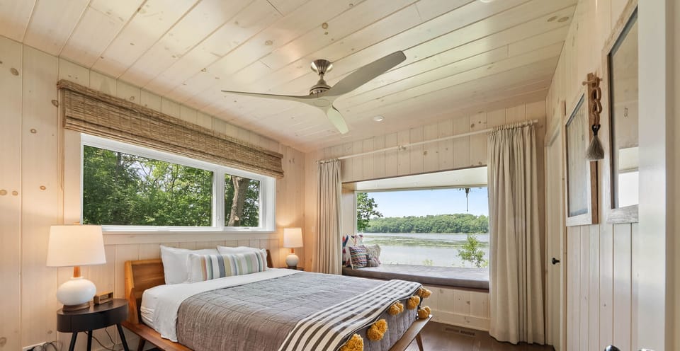 Wake up to lake views in this serene bedroom with a queen-size bed, built-in window nook overlooking the lake, complete with soft natural light and a peaceful atmosphere.