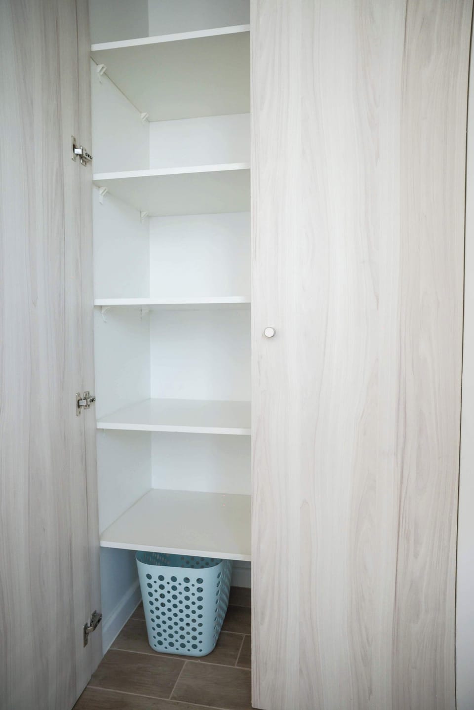 Organize your belongings with ease in this spacious closet featuring ample shelving and a handy laundry basket.