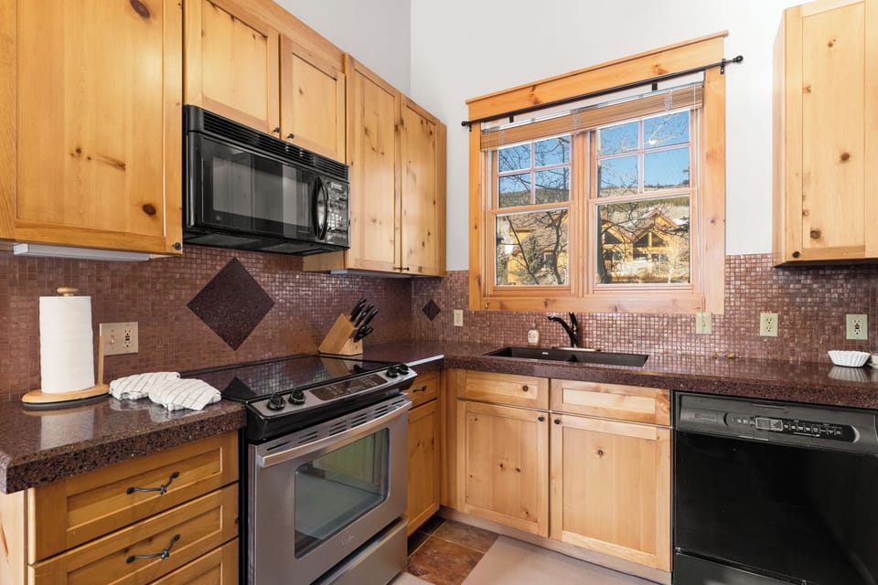Your fully equipped kitchen features rich wood cabinets, granite counters, and mountain views - perfect for preparing memorable meals during your stay.