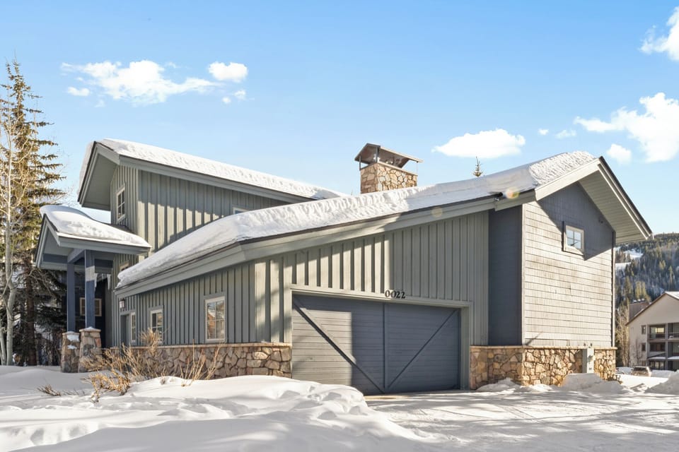Modern mountain home with stone and cedar siding, featuring a heated garage and scenic alpine backdrop.