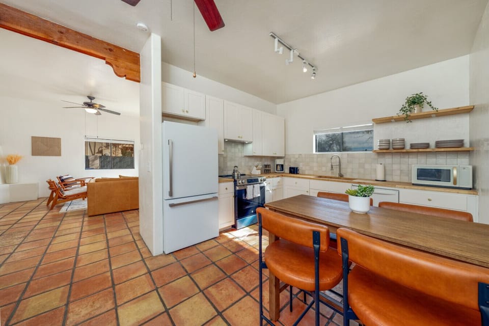 View of updated kitchen and living room, both with lovely terra cotta floors and plenty of natural light