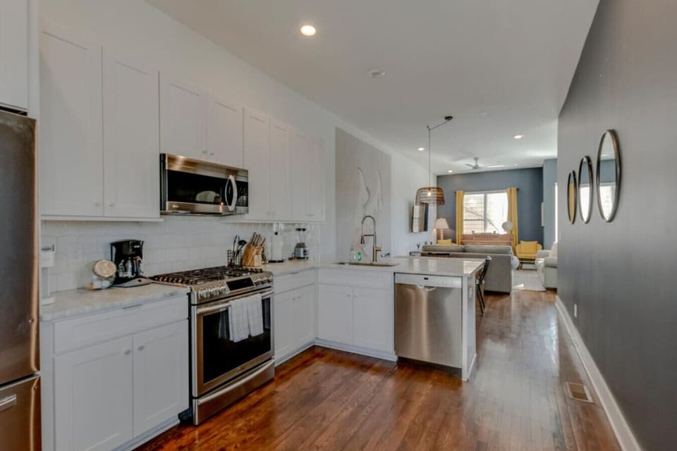 Kitchen with white cabinetry, stainless range, teal accent wall, and hardwood floors